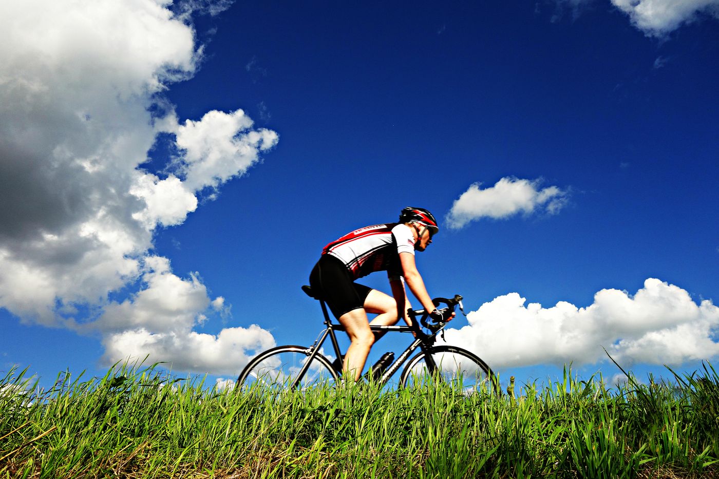 Radfahrer auf einer Landstraße unter blauem Himmel